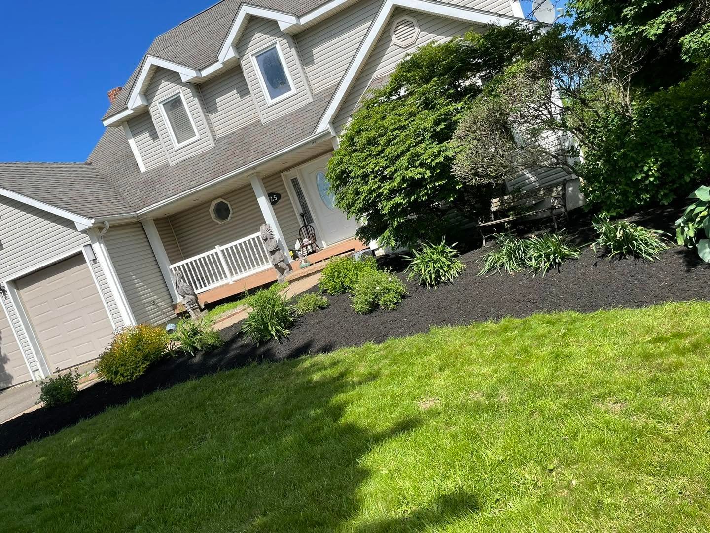 Landscaped front yard with a fresh garden bed and green lawn