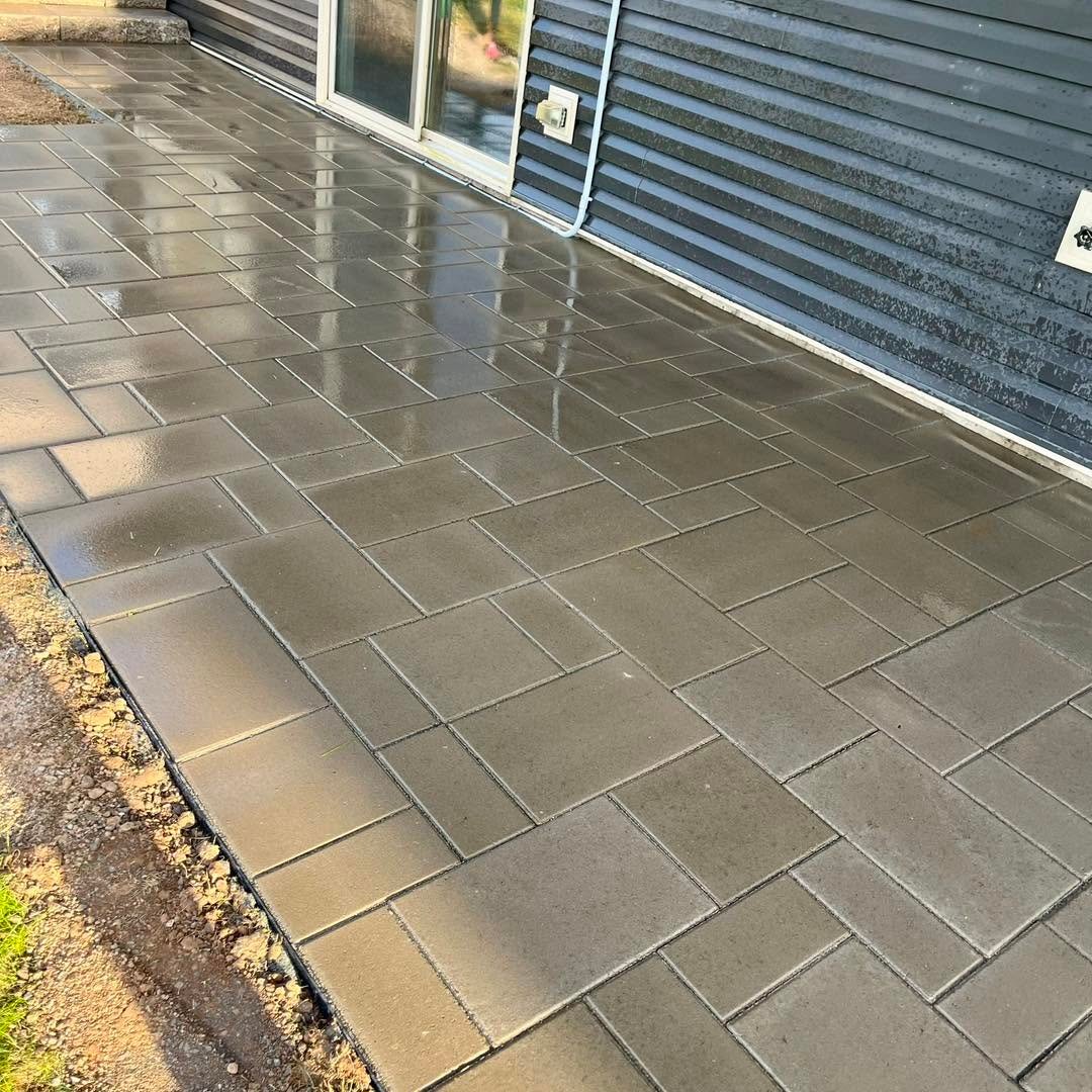 Newly completed grey paver patio after rainfall